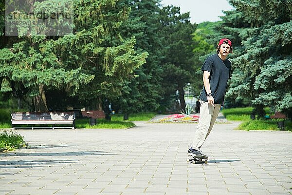 Langhaariger Skater Teenager in TShirt und Turnschuhmütze springt den Ollie vor dem Hintergrund eines stürmischen Himmels über der Stadt