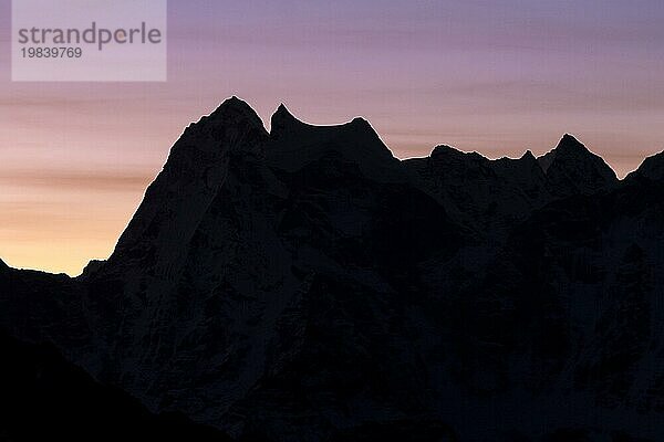 Silhouette des sechstausend Meter hohen Kangtega im Gegenlicht der aufgehenden Sonne  gesehen in der Morgendämmerung an einem Novembertag. Fotografiert vom Gokyo Ri  dem beliebten Trekking Gipfel in der Everest Region. Herbst  Nachmonsun Trekking Saison. Drei Pässe Trek  Khumbu  Everest Region  Himalaya. Sagarmatha Nationalpark  ein UNESCO Weltkulturerbe. Solukhumbu  Nepal  Asien