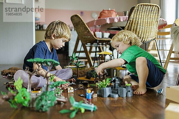 Children  four and two years old  playing with Playmobil on the floor in the living room