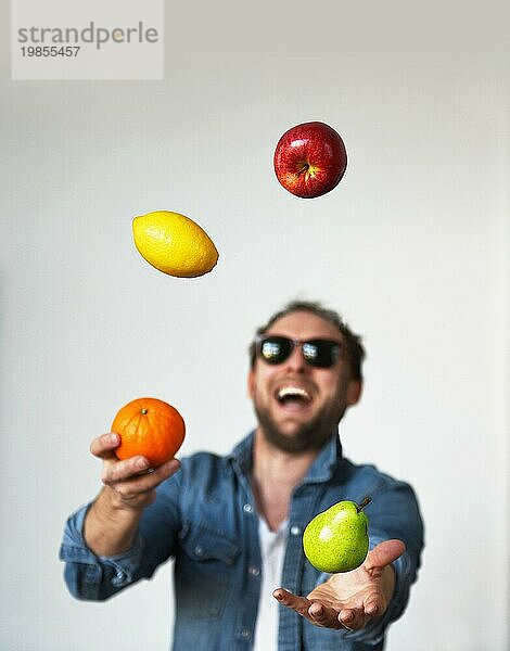 Mannn jongliert mit Obst