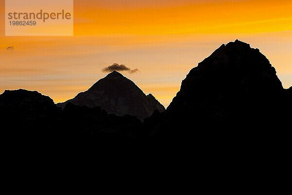 Silhouette des Achttausenders Makalu  des fünfthöchsten Berges der Erde  im Gegenlicht der aufgehenden Sonne  mit einer kleinen Wolke über dem Gipfel  in der Morgendämmerung eines Novembertages. Fotografiert vom Gokyo Ri  dem beliebten Trekking Gipfel in der Everest Region. Herbst  Nachmonsun Trekking Saison. Gokyo Trek  Khumbu  Everest Region  Himalaya. Der Sagarmatha Nationalpark  ein UNESCO Weltnaturerbe. Solukhumbu  Nepal  Asien