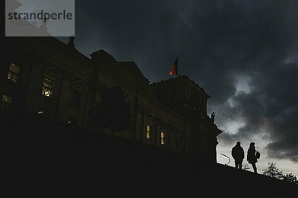 Two people stand out in front of the German Bundestag at blue hour in Berlin  15/11/2023