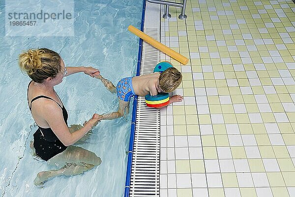 Thema: Vorschulkind beim Schwimmunterricht mit Schwimmflügeln in einem öffentlichen Bad