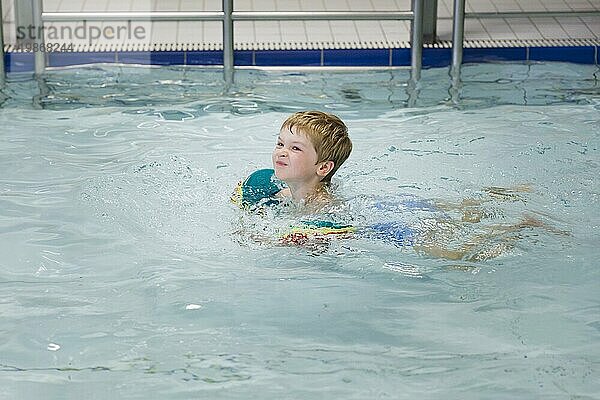 Thema: Vorschulkind im Schwimmbad mit Schwimmflügeln in einem öffentlichen Bad