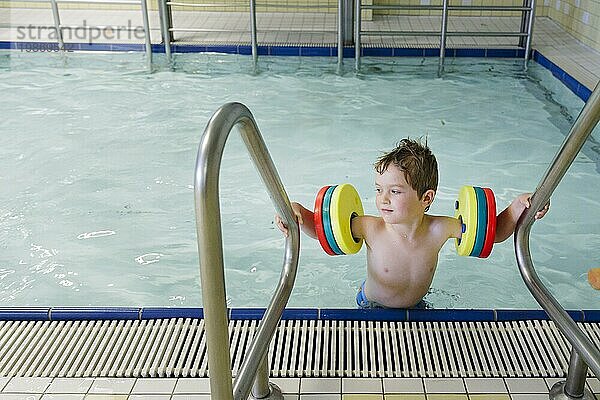Thema: Vorschulkind mit Schwimmflügeln im Schwimmbad lernt schwimmen in einem öffentlichen Bad