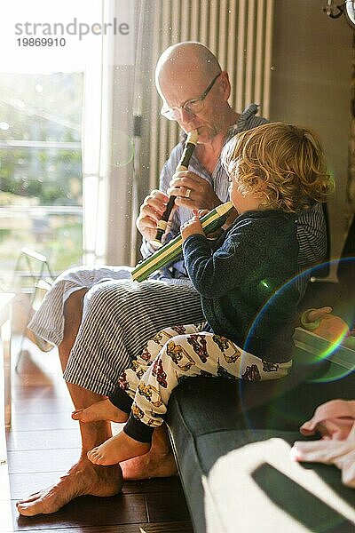 Thema: Familienkonzert  Kind spielt auf einer Melodika der Firma Höhner. Großvater und Onkelkind im Pyjama