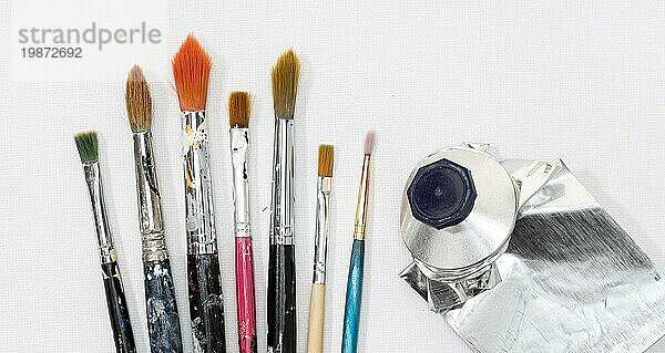 Künstler Pinsel und Squeeze Ölfarbe Rohr auf weißer Leinwand Hintergrund
