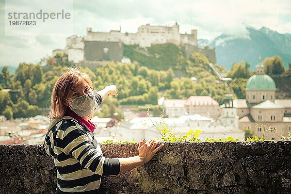 Weibliche Touristin mit Gesichtsmaske genießt den Blick über die Altstadt von Salzburg