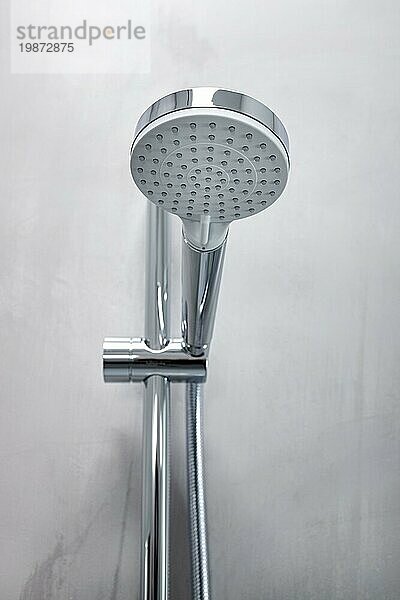 Duschkopf an einer grauen Mikrozementwand in einem modernen Badezimmer