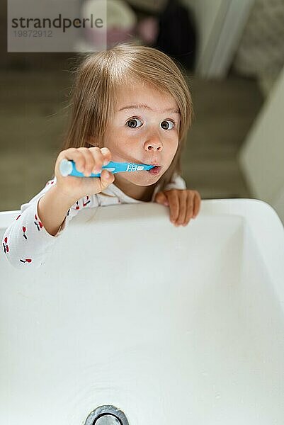 Baby Mädchen in hellen Bad Bürsten ihre Zähne über dem Waschbecken. 23 Jahre altes Kind persönliche Hygiene