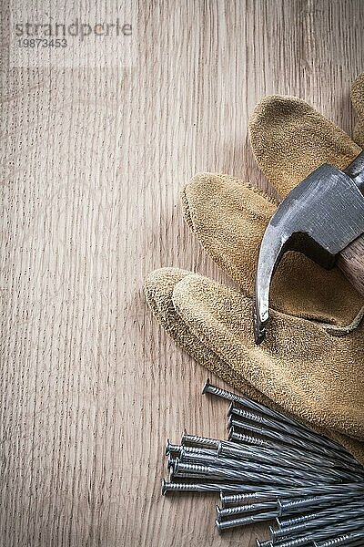 Klauenhammer Lederschutzhandschuhe und Metallnägel auf Holzbrett Draufsicht Baukonzept