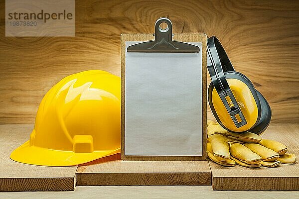 Baukonzept. Sicherheit der Arbeit. leeres Papierblatt in Zwischenablage gelber Helm Lederhandschuhe Kopfhörer