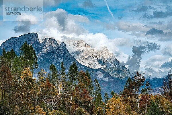 Blick auf das Bergmassiv des Framont und der Civetta von Süden nach Norden an einem strahlenden Herbsttag mit farbigen Bäumen im Vordergrund