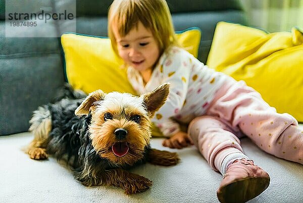 Kind mit einem Yorker Hund auf einem Sofa