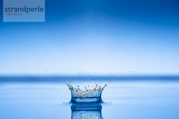 Wassertropfen spritzt in blaue Wasseroberfläche Gesundheit und Reinheit Konzept