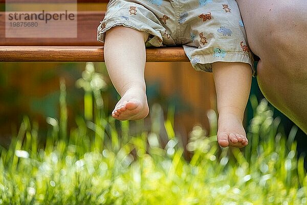 Baby aufwachsen Konzept: Close up von barfuß Baby Füße sitzen auf Parkbank  Sommerzeit