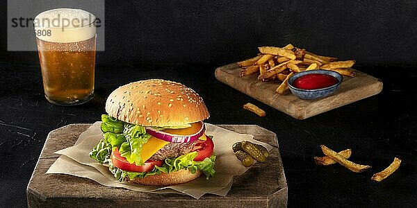 Burger mit Pommes frites und Bier Panorama. Hamburger mit Rindfleisch  Käse  Zwiebel  Tomate und grünem Salat  auf dunklem Hintergrund. Selektiver Fokus