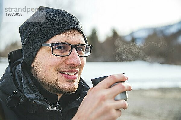 Kaukasischer Mann hält eine Tasse Tee im Freien  Winterzeit