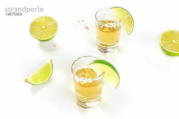 Goldener Tequila mit Limettenscheiben und Salz  Schnapsgläser auf weißem Hintergrund mit Platz für Text