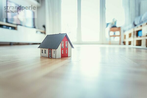 Rotes Hausmodell auf dem Boden  drinnen. Konzept für neues Haus  Grundstück und Anwesen