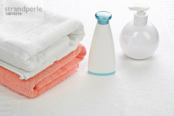 Flaschen mit zwei Handtüchern auf weißem Hintergrund