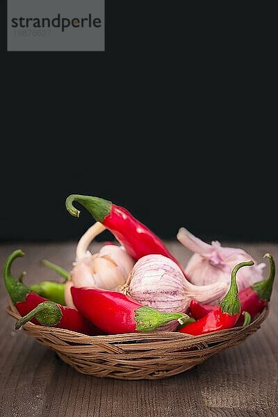 Lebensmittelstillleben mit Knoblauch  grünen und roten Chilischoten mit schwarzem Kopierraum