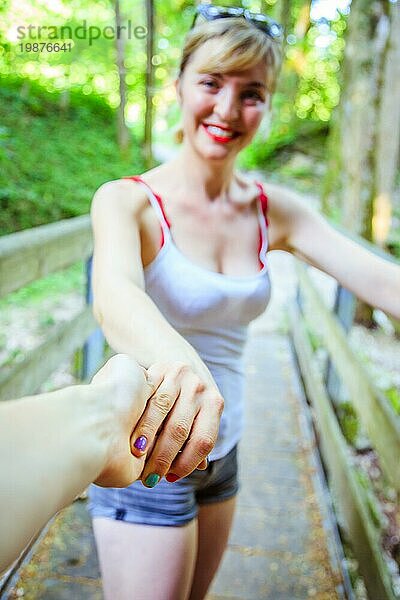 Junges Mädchen hält ihre Hand zu ihrem Freund  draußen im Wald