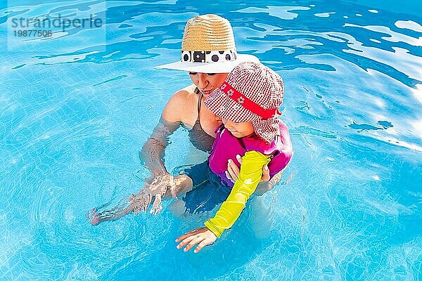 23 Jahre altes Kind mit Mutter im Schwimmbad lernen zu schwimmen. Baby im Schwimmen Westen und roten Hut.Sommer zu Hause Konzept. Oben schießen