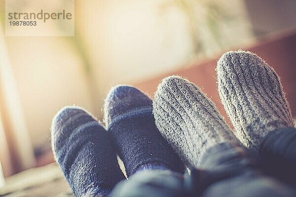 Füße mit Wollsocken in der Winterzeit: Pärchen entspannt auf der Couch