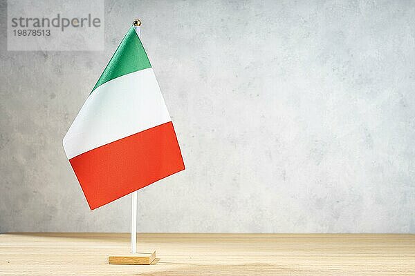 Italienische Tischflagge auf weißer  strukturierter Wand. Kopierraum für Text  Entwürfe oder Zeichnungen