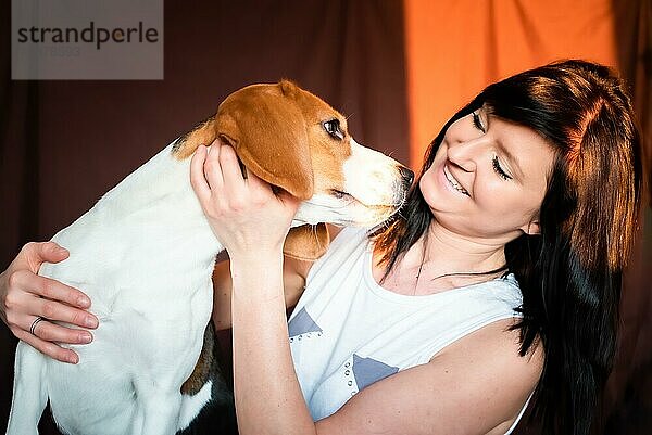 Junge Frau kuschelt mit Beagle Hund in hellem Interieur. Haustier Freundschaft Konzept