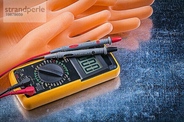 Digitales elektrisches Prüfgerät Elektriker Gummihandschuhe auf metallischem Hintergrund