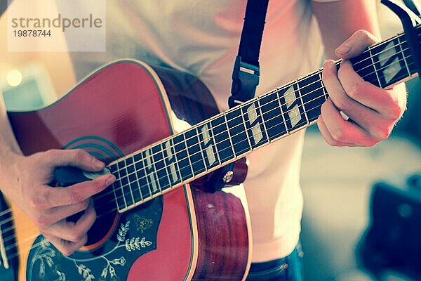 Junger Mann spielt eine Sunburst Westerngitarre: Ausschnitt  unscharf