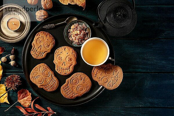 Halloween Ingwerplätzchen in Form von Totenköpfen  hausgemachte Dia de los muertos Kekse  von oben fotografiert mit Platz für Text auf dunklem Holzhintergrund