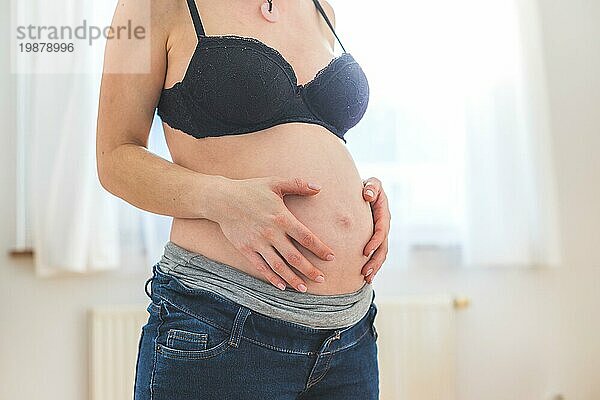 Nahaufnahme einer schwangeren kaukasischen Mutter  die ihren nackten Bauch berührt