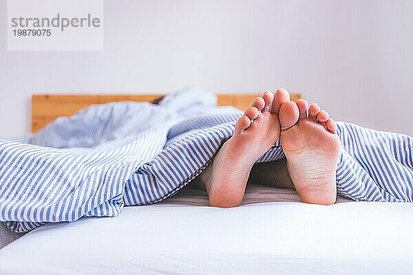 Nahaufnahme unbedeckte weibliche erwachsene Füße im Bett schlafend  morgens