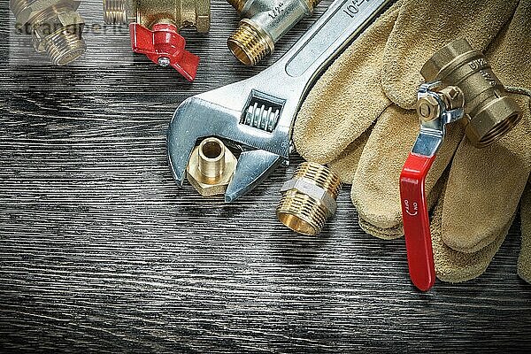 Verstellbarer Schraubenschlüssel für Wasserventile Rohrverschraubungen Lederschutzhandschuhe auf Holzbrett