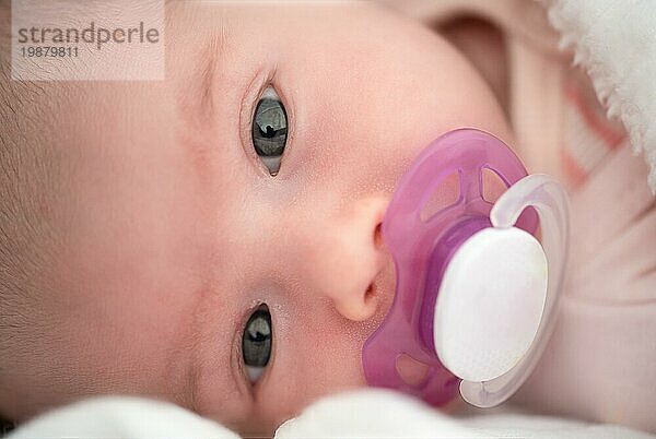 Close up von Newborn Baby liegt auf der Seite mit weißen Schnuller im Mund. Neugeborenes Thema