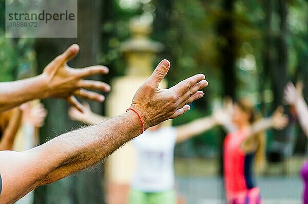 Die Hände und Handflächen der Menschen werden zum Yoga im Park erhoben
