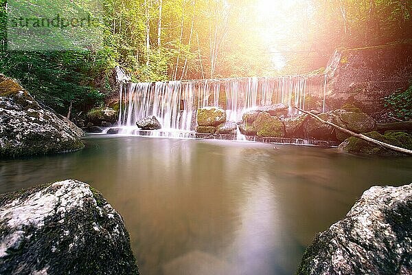 Schöner Bergwasserfall und Sonnenlicht im Wald  Langzeitbelichtung. Österreich