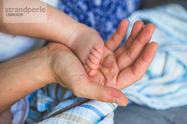 Nahaufnahme der Hände der Mutter  die die Füße des neugeborenen Babys halten