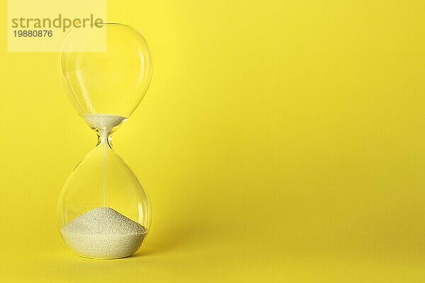 Die Zeit läuft ab Konzept. Eine Sanduhr auf einem leuchtend gelben Hintergrund mit einem Platz für Text