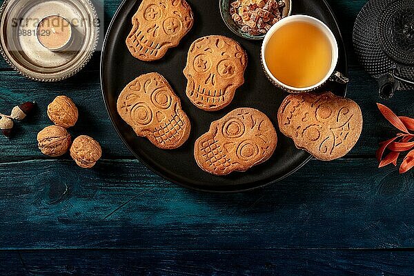 Halloween Ingwerplätzchen in Form von Totenköpfen  selbstgebackene Dia de los muertos Kekse  Aufnahme von oben Hexenkopierraum auf einem dunklen Holzhintergrund