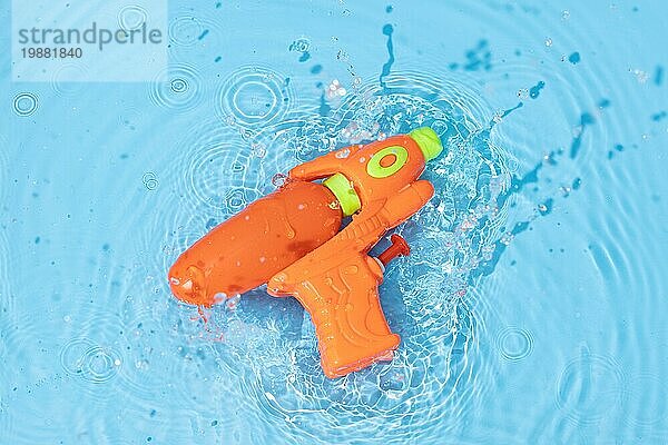 Wasserpistole Spielzeug spritzt auf blaue Wasseroberfläche Spaß  Freizeit Sommerzeit Hintergrund