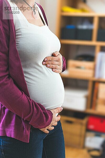 Nahaufnahme eines schwangeren Bauches  kaukasische Mutter mit weißem Hemd und magentafarbener Jacke