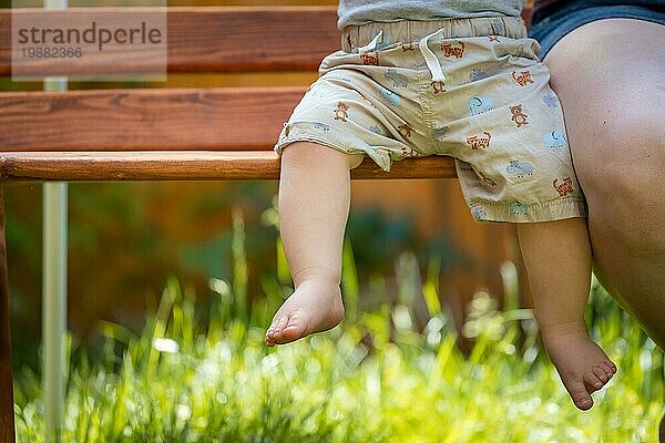 Baby aufwachsen Konzept: Close up von barfuß Baby Füße sitzen auf Parkbank  Sommerzeit
