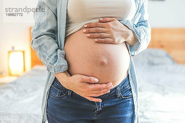 Kaukasische schwangere Mutter  die ihren nackten Bauch berührt  Blue Jeans  Nahaufnahme