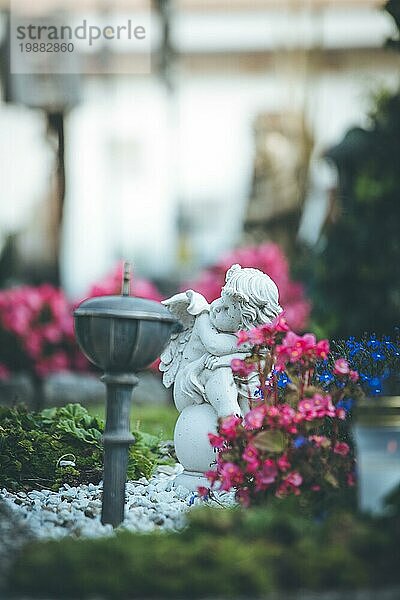 Weißer Engel auf einem Grab auf einem Friedhof  Blumen