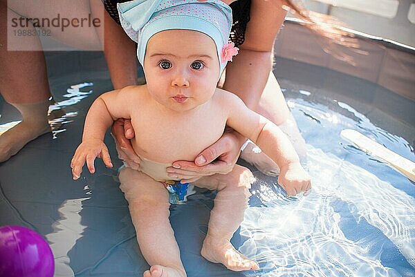 Mutter hält ihr kleines Mädchen zum ersten Mal im Schwimmbad. Sommeraktivitäten