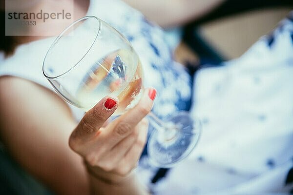 Schönes junges Mädchen mit blondem Haar hält ein Glas Wein und lächelt  Ferien